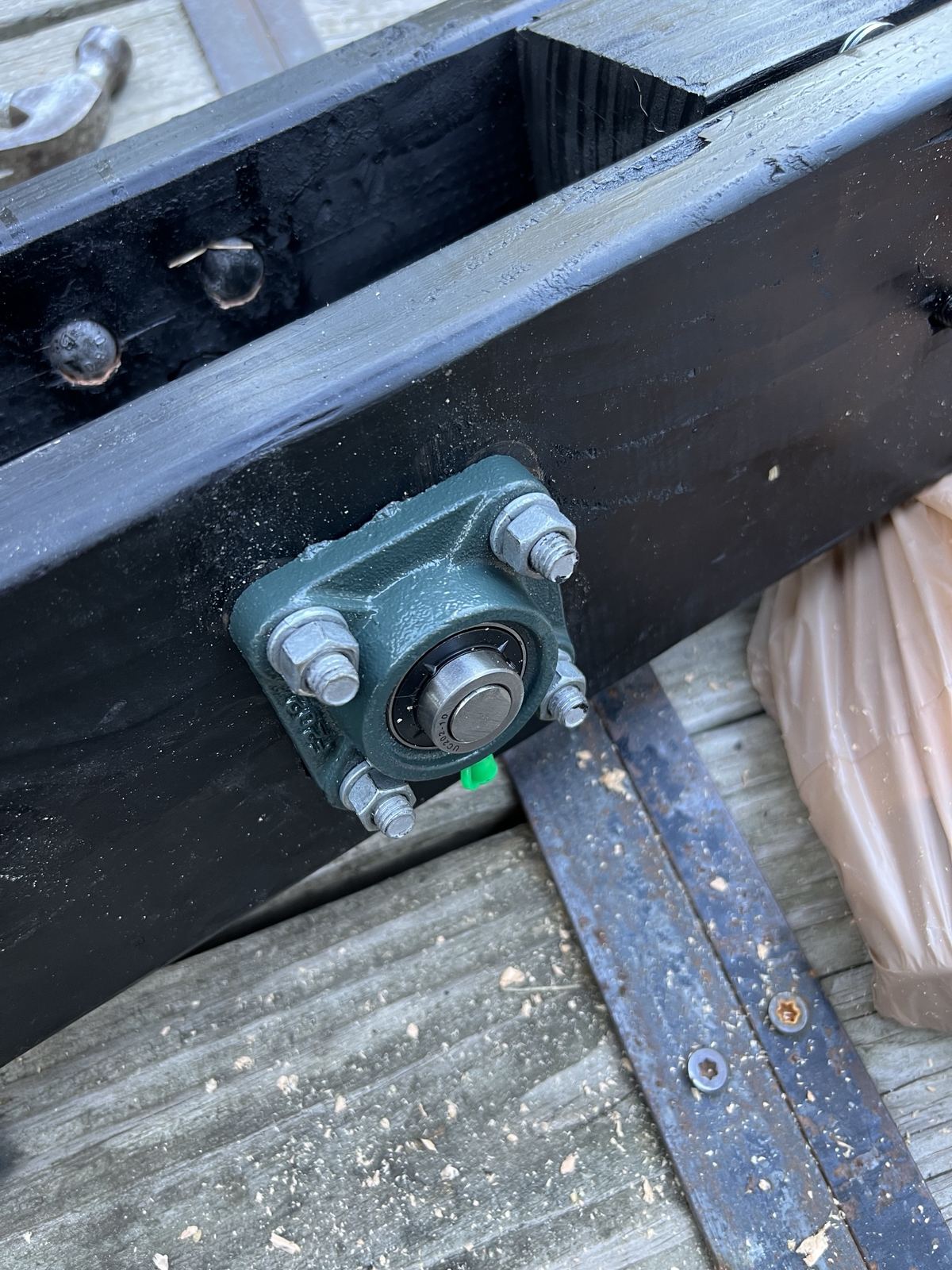 Close-up of a pillow-block bearing bolted to black timber